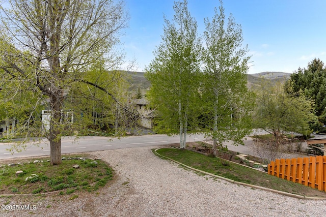 view of property's community featuring curved driveway, fence, and a mountain view