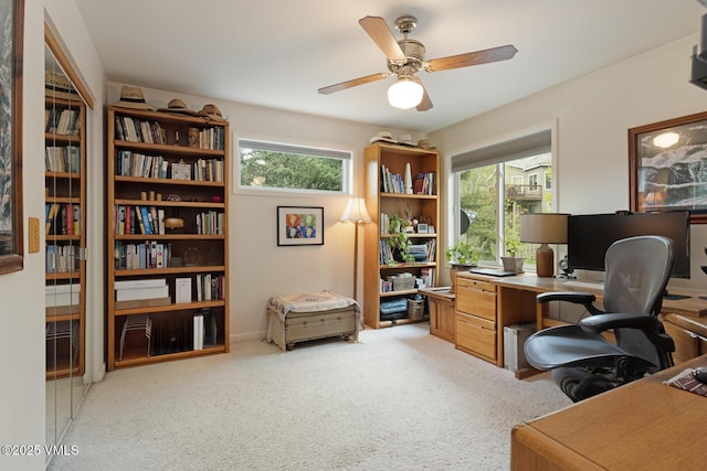 home office featuring healthy amount of natural light, a ceiling fan, and light carpet