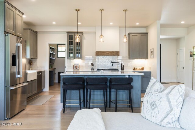 207 Aidan Rd, Eagle, CO 81631 - kitchen with stainless steel refrigerator with ice dispenser, tasteful backsplash, light wood-style floors, light countertops, and a breakfast bar
