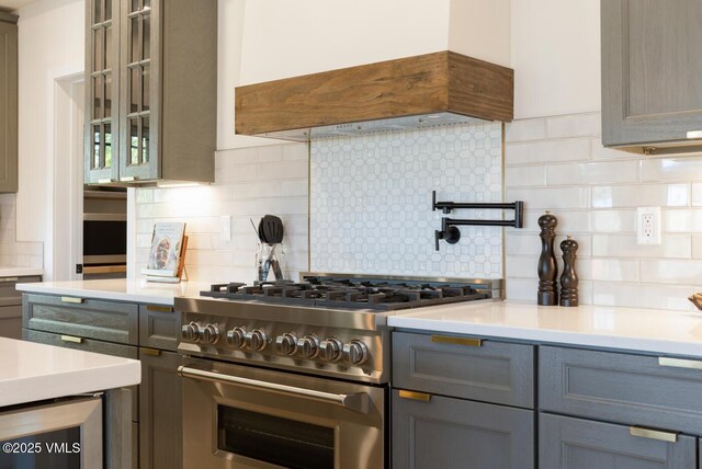 207 Aidan Rd, Eagle, CO 81631 - kitchen with high end stainless steel range oven, custom exhaust hood, gray cabinets, decorative backsplash, and light countertops