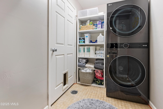 laundry room featuring stacked washer / dryer and baseboards