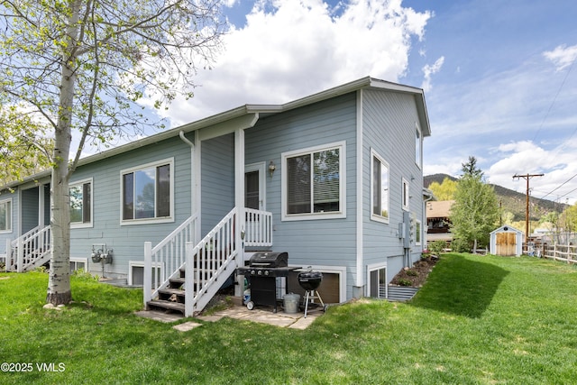back of house featuring a storage shed, a yard, and an outbuilding