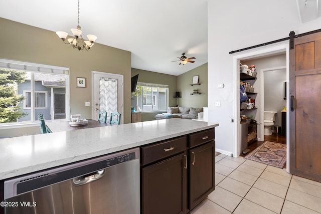 kitchen with stainless steel dishwasher, a barn door, light tile patterned flooring, ceiling fan, and hanging light fixtures