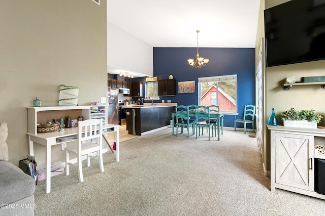 dining area with a chandelier, light colored carpet, and high vaulted ceiling