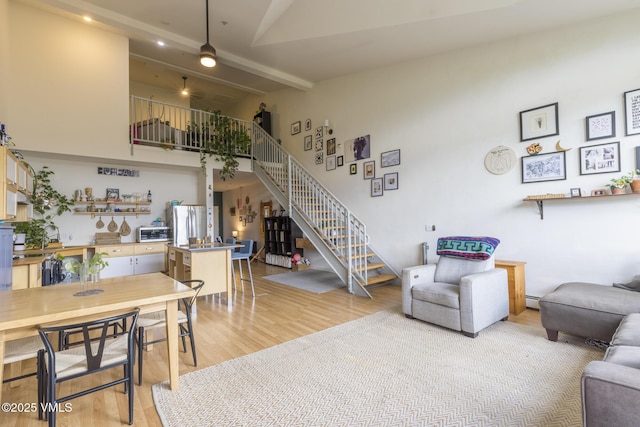 705 Nogal Rd Unit C9, Eagle, CO 81631 - living room featuring stairway, light wood-style flooring, beam ceiling, a baseboard heating unit, and high vaulted ceiling