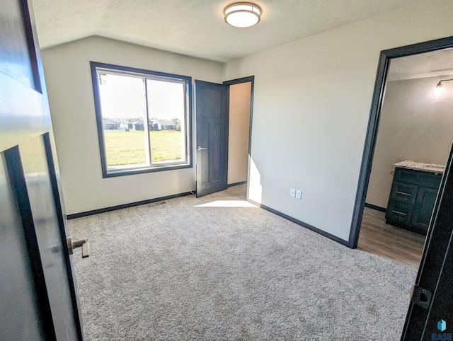 unfurnished bedroom featuring light carpet and a textured ceiling