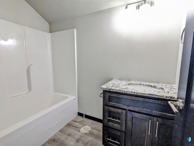 bathroom with hardwood / wood-style floors, a textured ceiling, vanity, and shower / tub combination