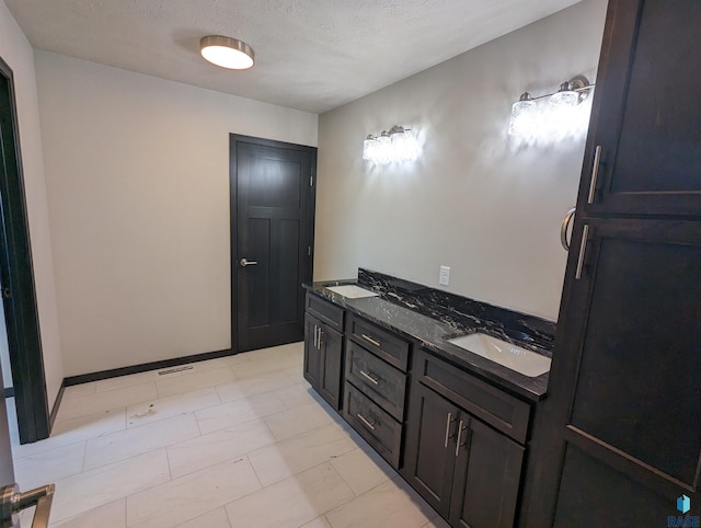 bathroom featuring tile flooring, double vanity, and a textured ceiling