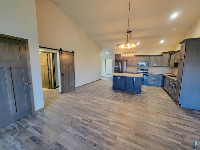 kitchen featuring a barn door, light hardwood / wood-style flooring, a center island, and refrigerator with ice dispenser