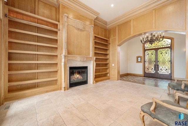 living room featuring a chandelier, built in shelves, french doors, and ornamental molding