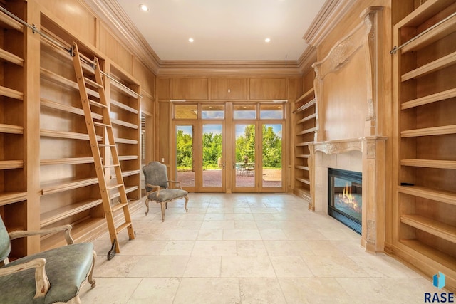 unfurnished room featuring built in shelves, crown molding, french doors, and wood walls