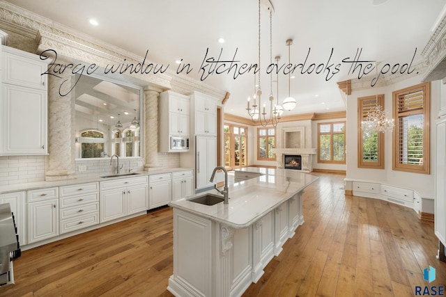 kitchen featuring sink, ornamental molding, an island with sink, and stainless steel microwave