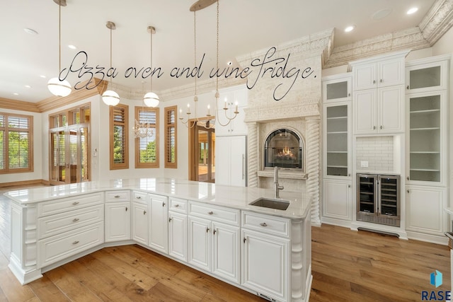 kitchen featuring wine cooler, decorative light fixtures, white cabinetry, and sink