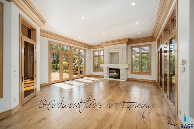 unfurnished living room with french doors, a high end fireplace, light hardwood / wood-style floors, and ornamental molding