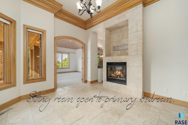 unfurnished living room with a chandelier, crown molding, and a tiled fireplace