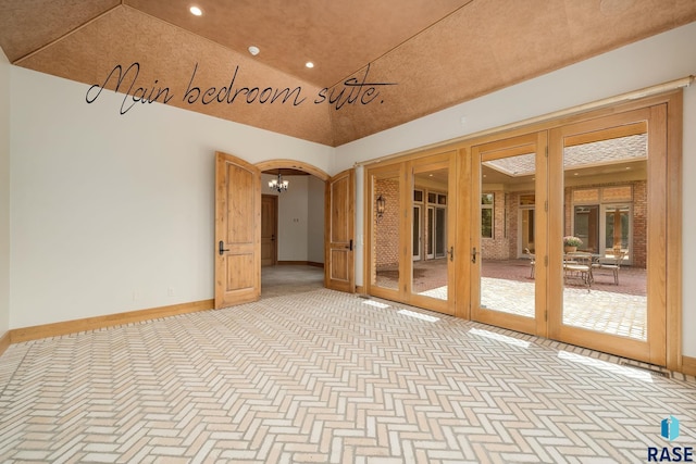 empty room featuring french doors, vaulted ceiling, and an inviting chandelier