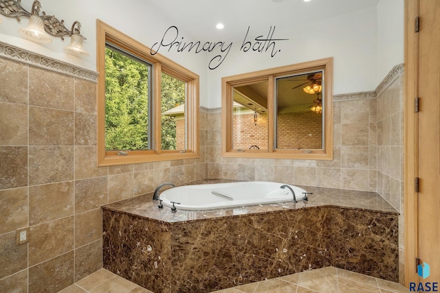 bathroom with ceiling fan, tile patterned flooring, a relaxing tiled tub, and tile walls