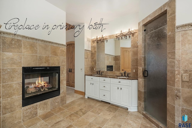 bathroom featuring a fireplace, vanity, tile walls, and walk in shower