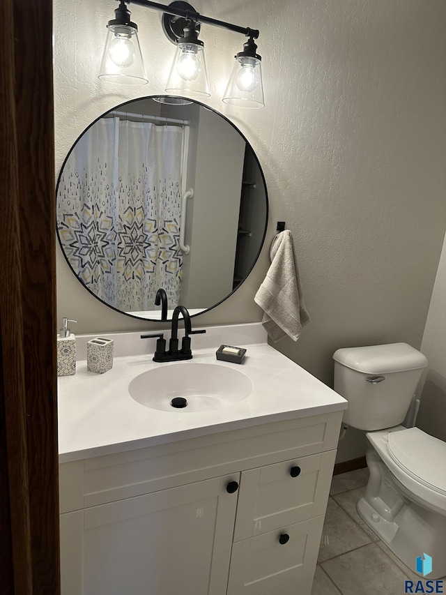 bathroom with tile patterned flooring, vanity, and toilet