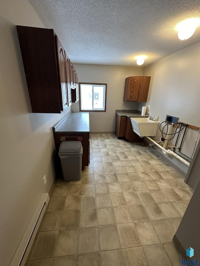 kitchen with a textured ceiling, baseboard heating, and sink