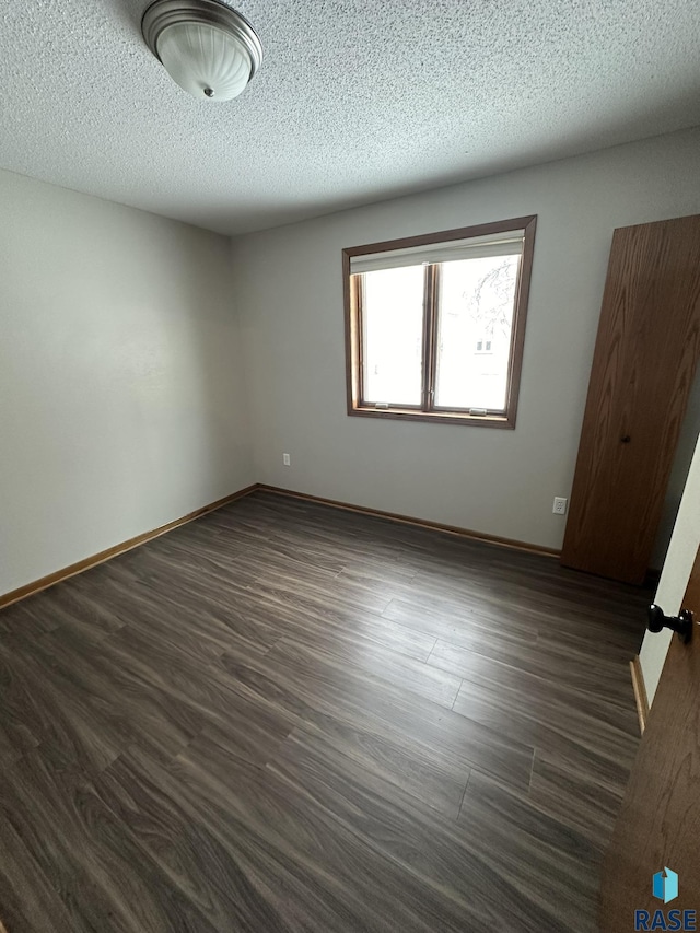 spare room with a textured ceiling and dark wood-type flooring