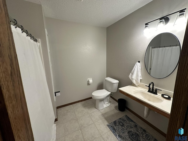 bathroom with a textured ceiling, toilet, and sink