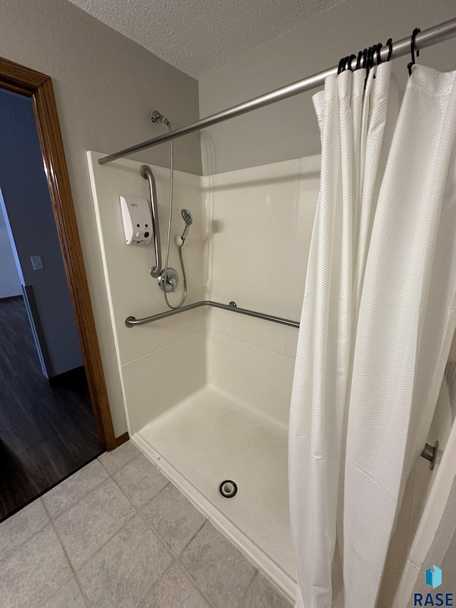 bathroom with a shower with curtain, a textured ceiling, and tile patterned floors