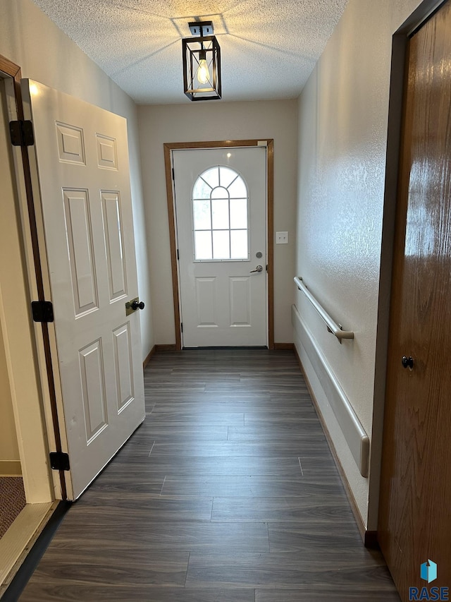 doorway to outside with dark hardwood / wood-style flooring and a textured ceiling