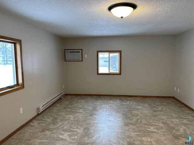 unfurnished room featuring a wall unit AC, a textured ceiling, and a baseboard heating unit