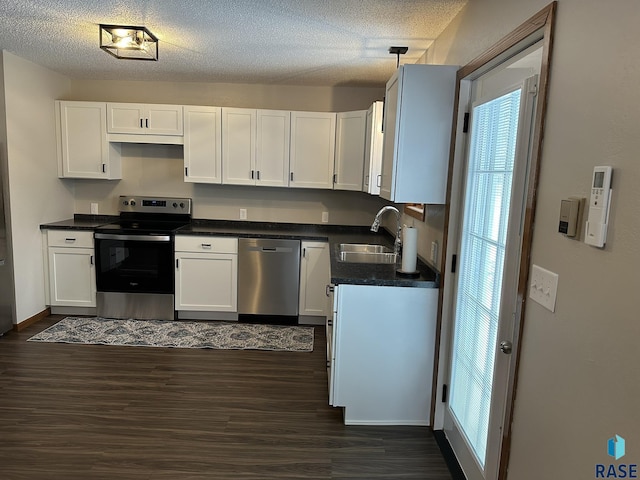 kitchen featuring decorative light fixtures, stainless steel appliances, white cabinetry, and sink