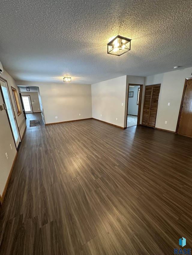 unfurnished living room featuring a textured ceiling and dark wood-type flooring