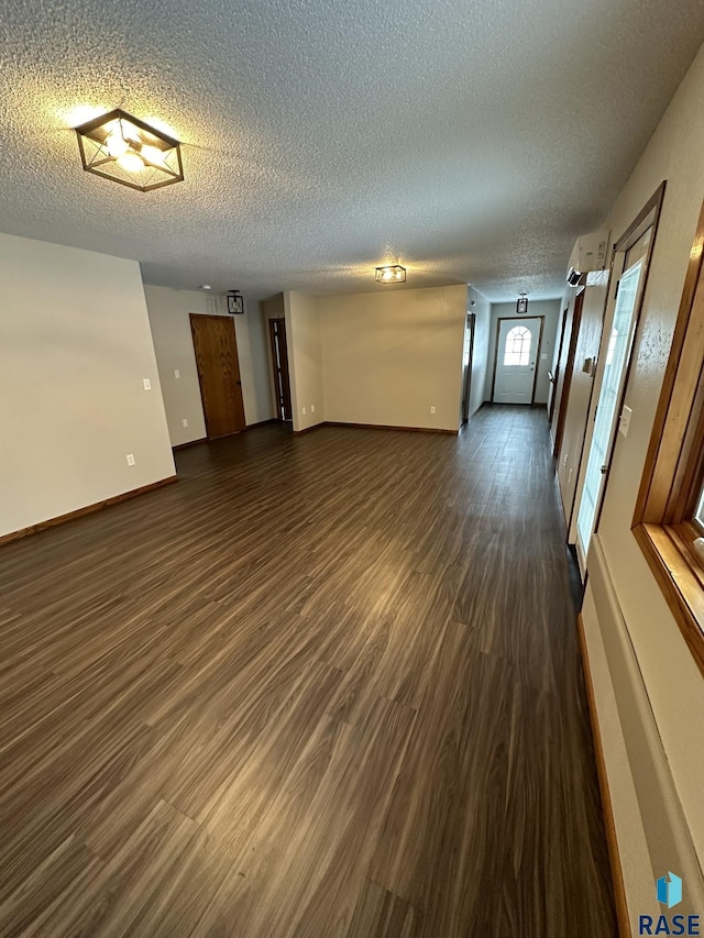 unfurnished room featuring a wall mounted AC, dark wood-type flooring, and a textured ceiling