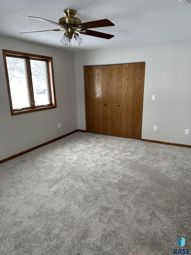 unfurnished bedroom featuring carpet flooring, a textured ceiling, a closet, and ceiling fan