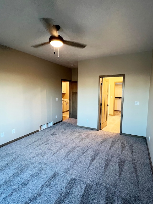 unfurnished bedroom with ensuite bath, light colored carpet, and ceiling fan