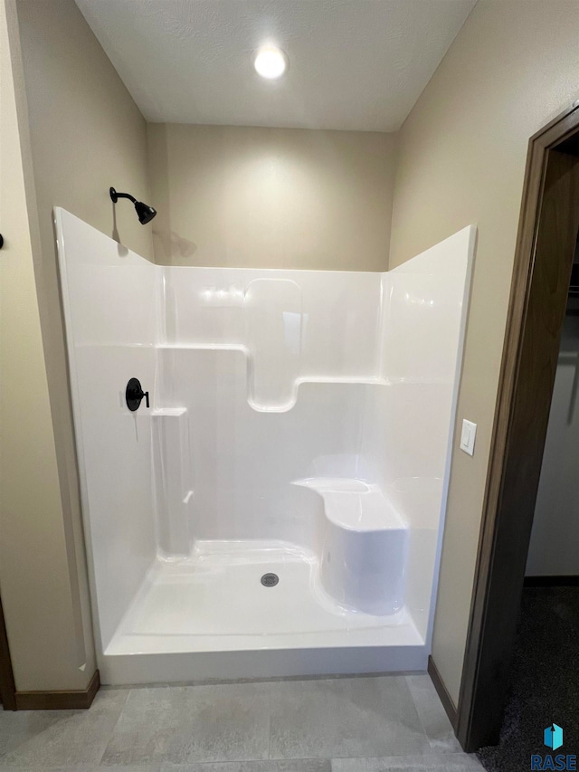 bathroom with a textured ceiling, tile floors, and a shower