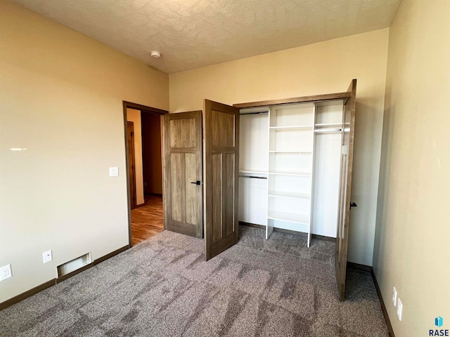 unfurnished bedroom with a closet and dark colored carpet