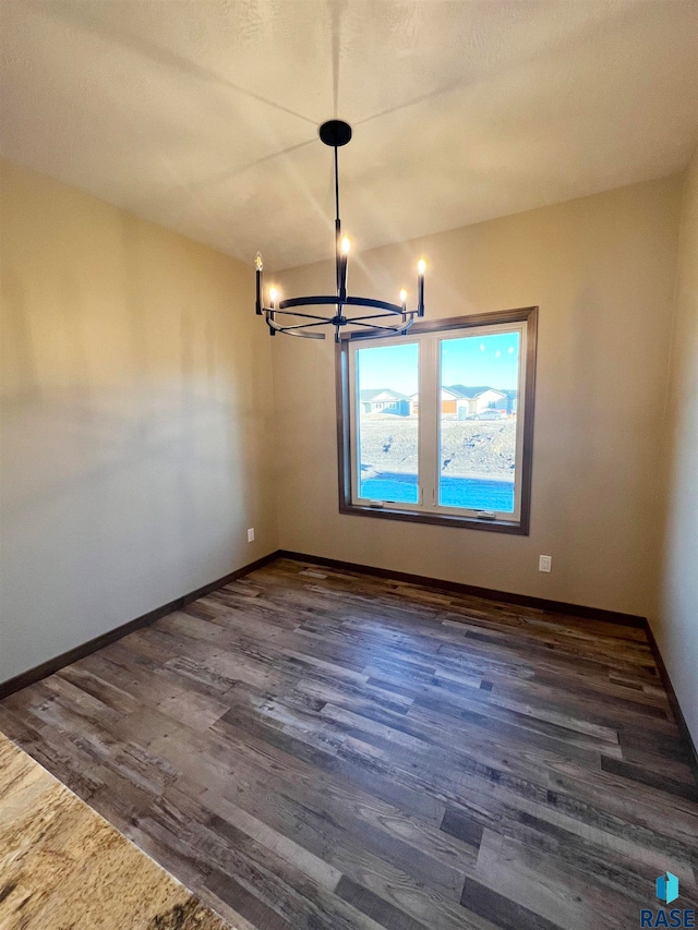 empty room featuring dark hardwood / wood-style floors and an inviting chandelier