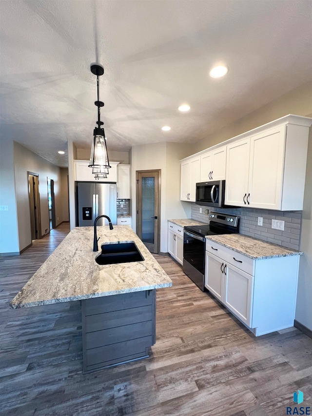 kitchen featuring stainless steel appliances, decorative light fixtures, hardwood / wood-style floors, white cabinetry, and sink