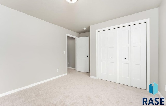 unfurnished bedroom featuring light colored carpet and a closet