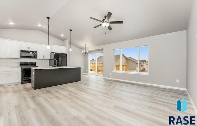 kitchen featuring backsplash, a kitchen island with sink, black appliances, white cabinets, and hanging light fixtures