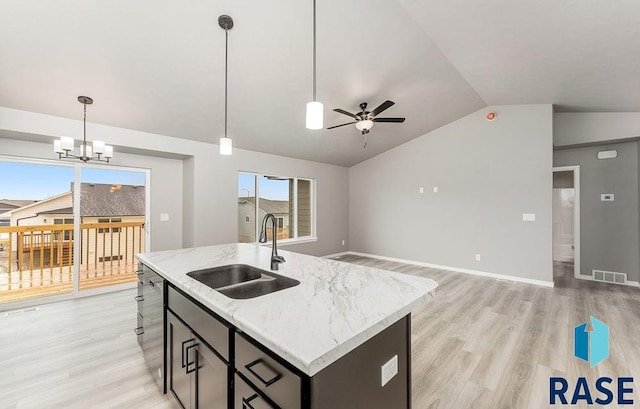 kitchen with ceiling fan with notable chandelier, vaulted ceiling, sink, a center island with sink, and hanging light fixtures