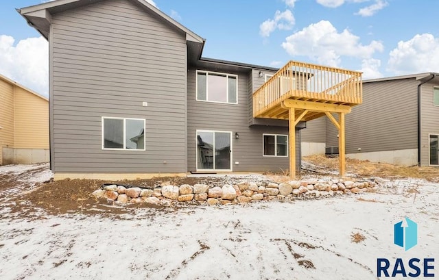 snow covered back of property with a deck and central air condition unit