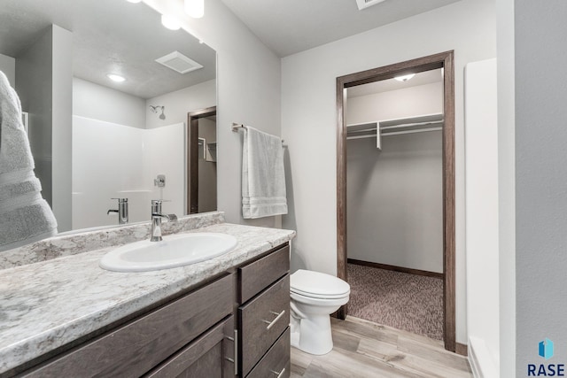 bathroom with hardwood / wood-style floors, vanity, toilet, and walk in shower