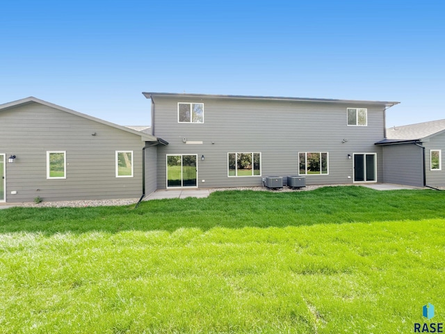 rear view of property with central air condition unit, a patio area, and a lawn