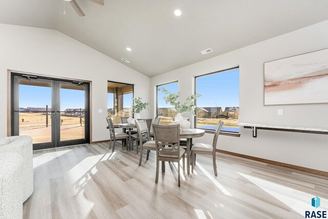 dining area with vaulted ceiling, light wood-type flooring, and french doors