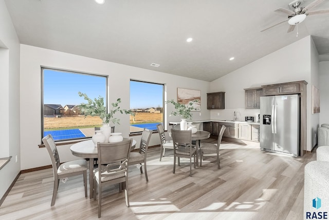 dining space featuring high vaulted ceiling, light hardwood / wood-style floors, and ceiling fan