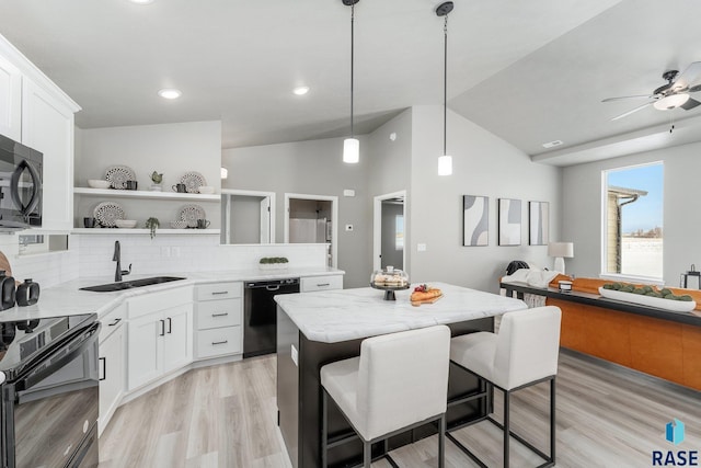 kitchen with white cabinetry, a center island, a kitchen bar, and black appliances