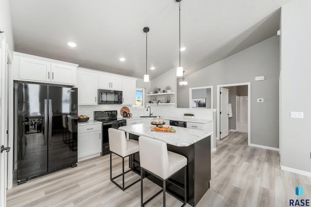 kitchen with sink, a breakfast bar, white cabinetry, black appliances, and decorative backsplash