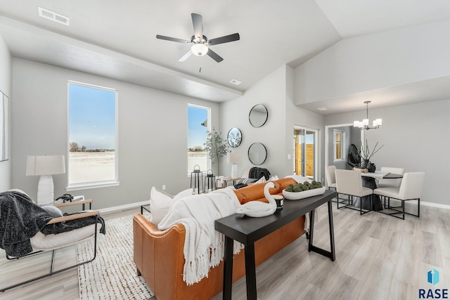 living room featuring vaulted ceiling, plenty of natural light, ceiling fan with notable chandelier, and light wood-type flooring