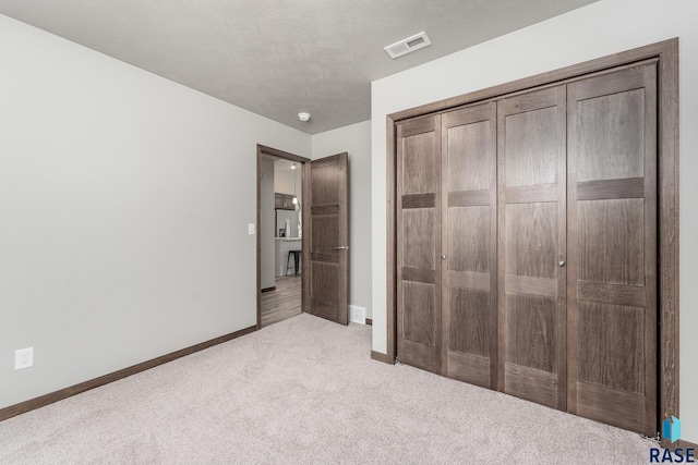 unfurnished bedroom with light carpet and a closet